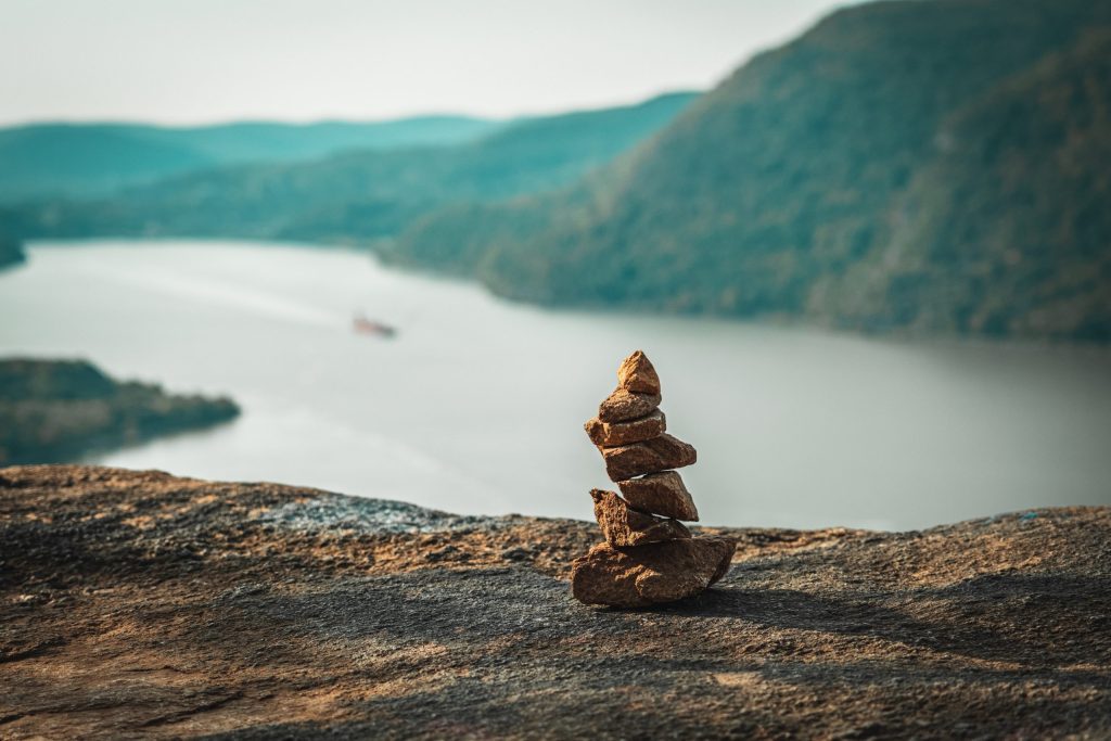 Cairn Above the Hudson A well-balanced stone cairn sits far above the Hudson River. A cargo ship can just barely be seen in the background.