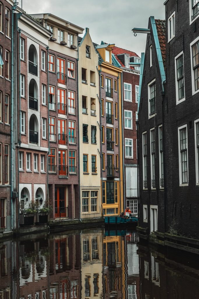 Amsterdam Canal A work boat floating in a canal with buildings on either side, and reflections on the surface of the water