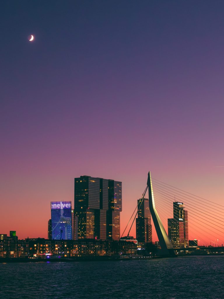 Rotterdam By Night A bridge and buildings in Rotterdam at sunset, with a crescent moon in the sky