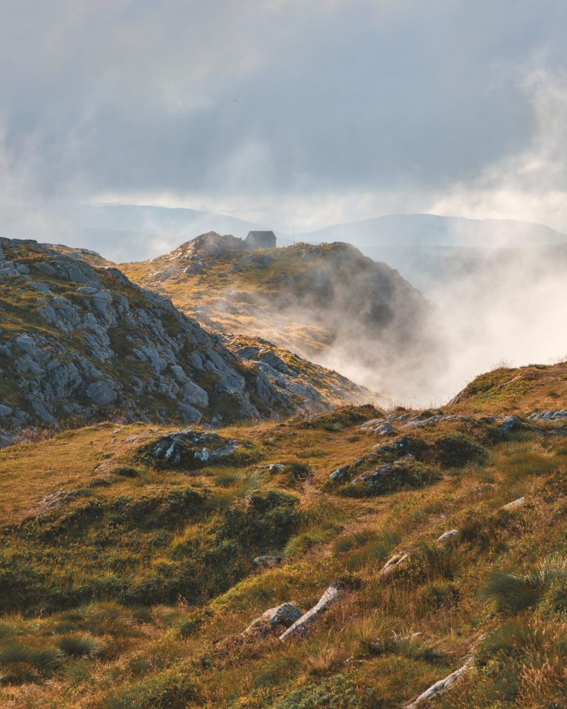 Peak of Ulriken The misty, grassy peak of a mountain with a small building visible