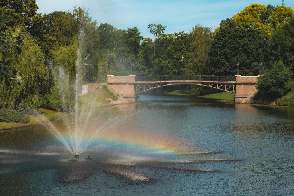 Fountain Rainbow A rainbow created by a fountain in a river with a bridge in the background