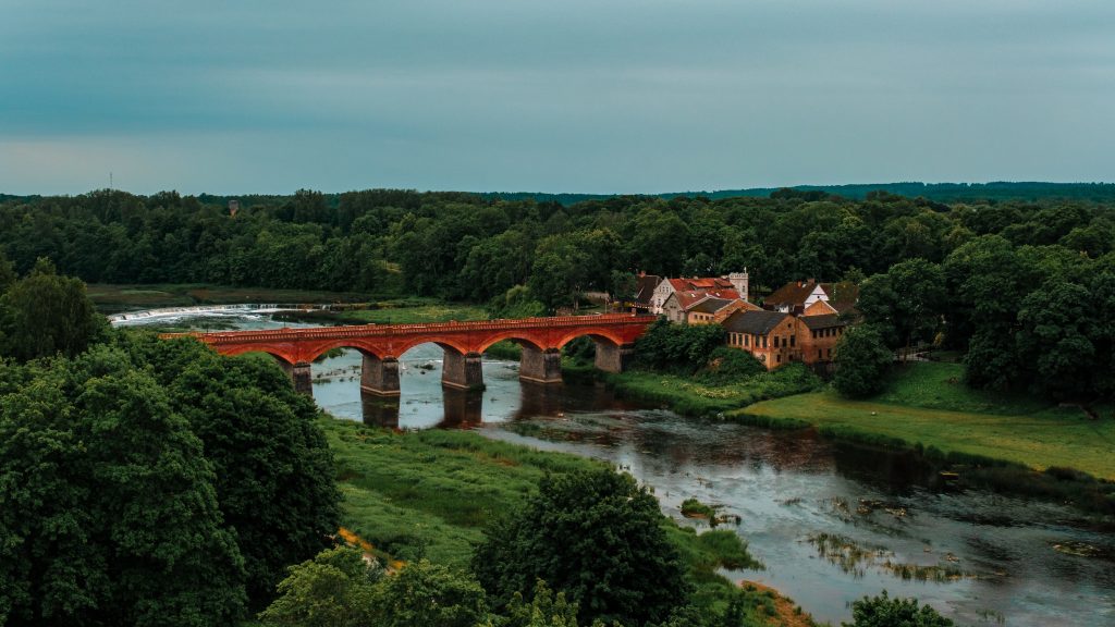 Kuldiga A brick bridge and small town surrounded by woods, with a wide waterfall in the background